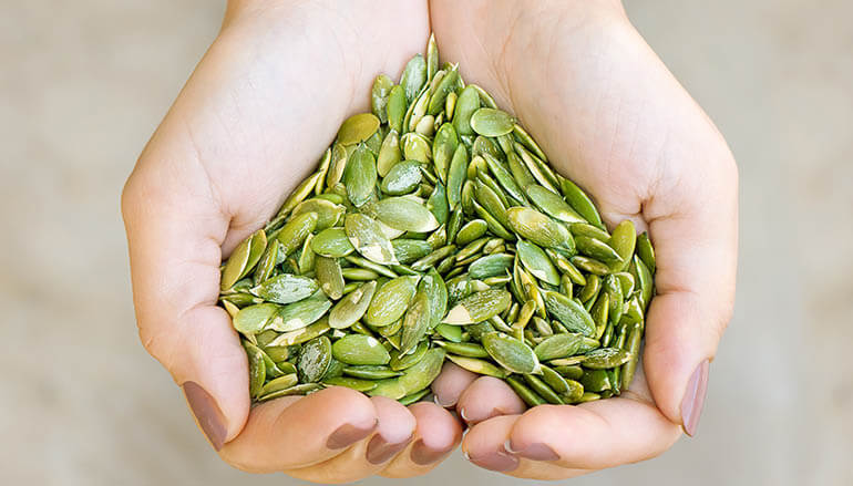 Hand holding pumpkin seeds